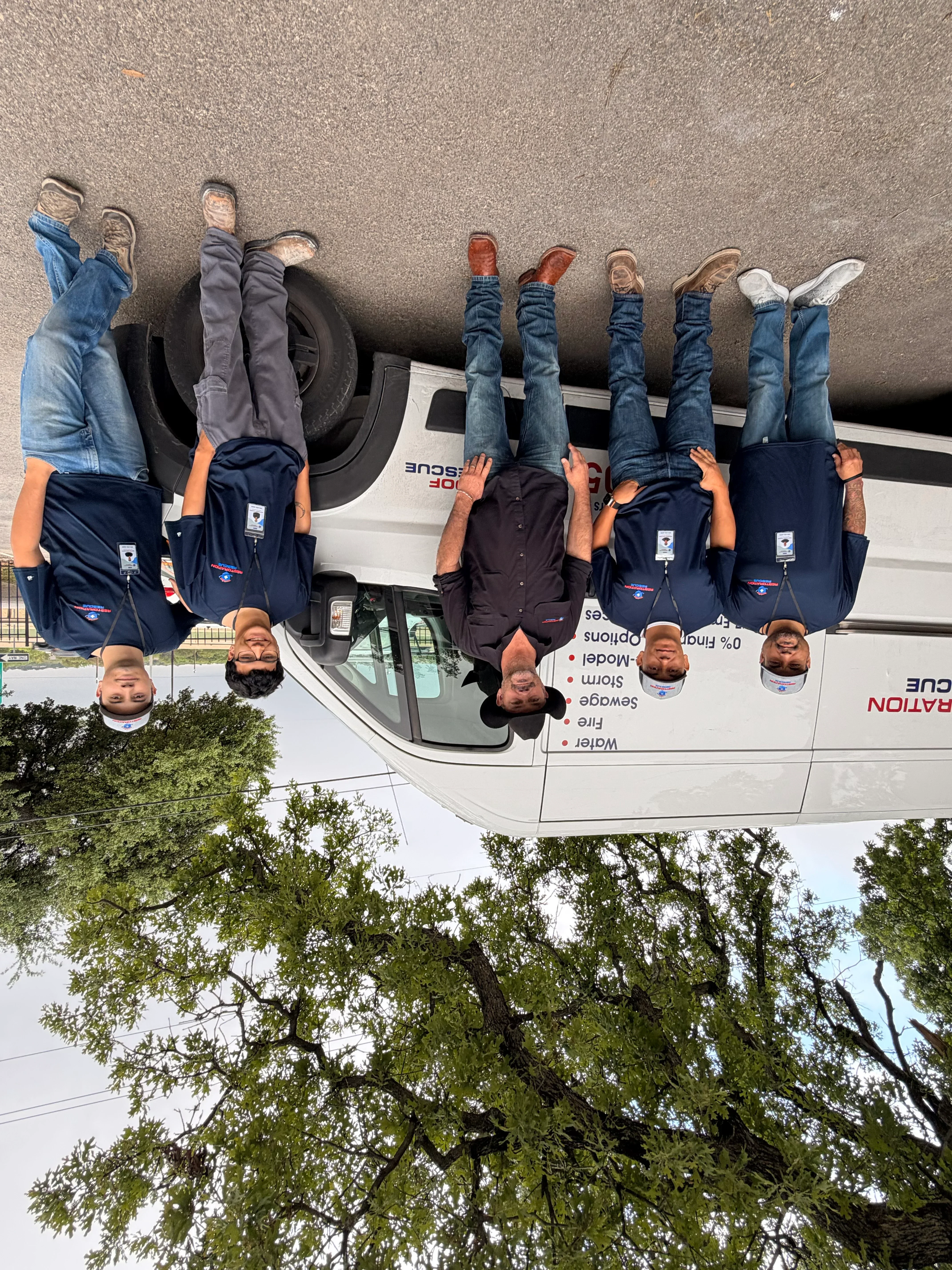 Professional water damage restoration team in branded uniforms standing beside service vehicle