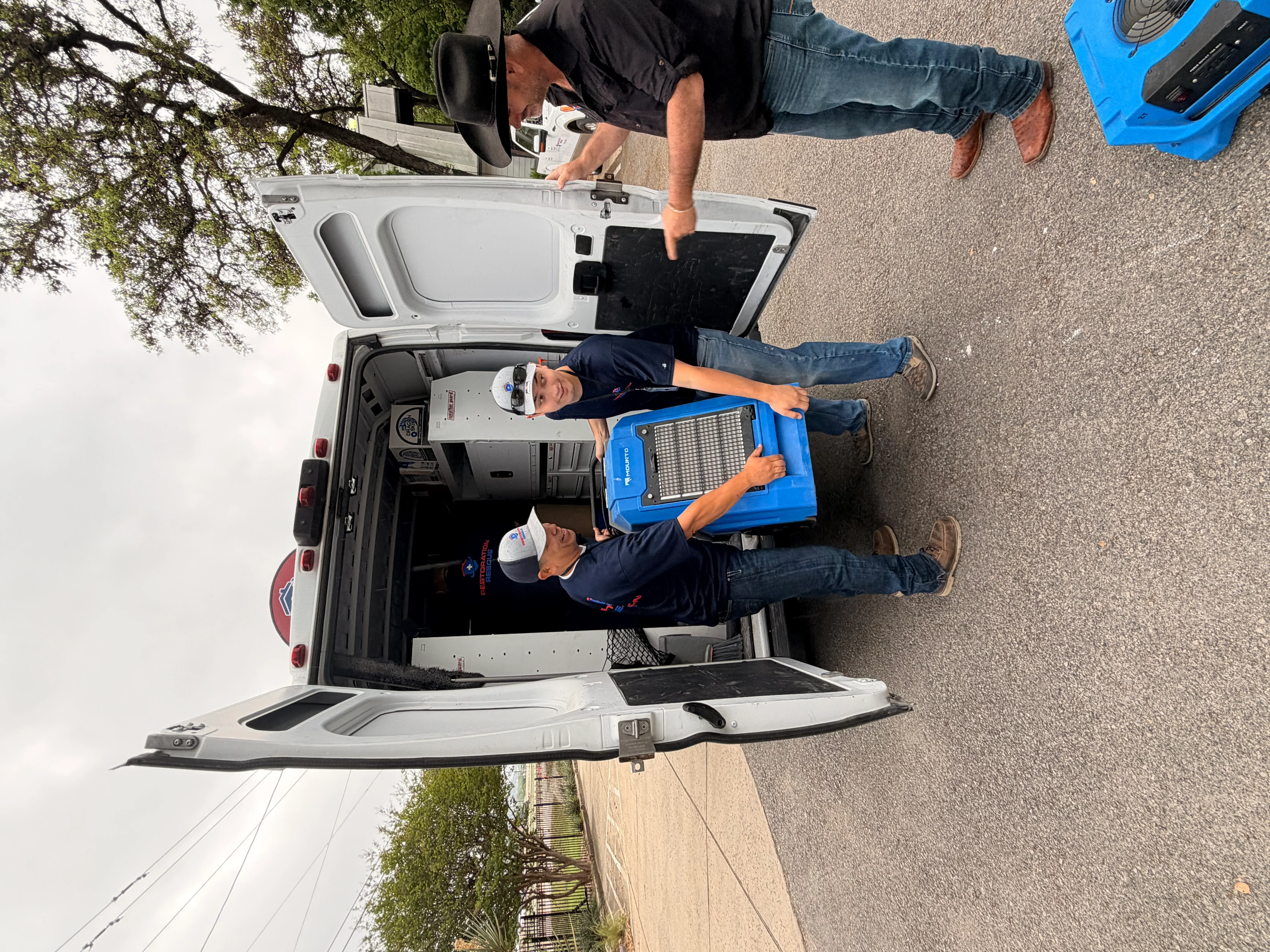 Technicians with industrial dehumidifier and moisture detection equipment at service vehicle